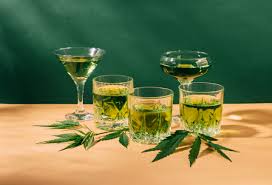 Glasses of cannabis infused drinks with hemp leaves on a table.